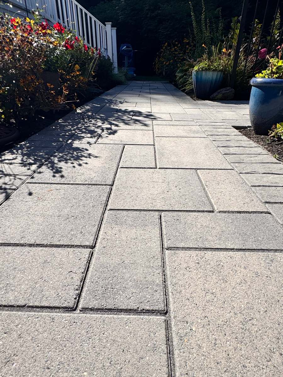 Paver garden walkway beside a white railing, cleaned and sealed in Rhode Island